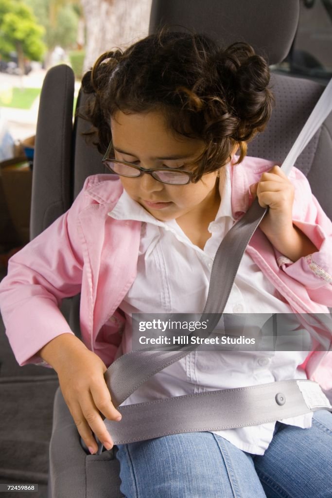 Girl fastening seatbelt in backseat of car