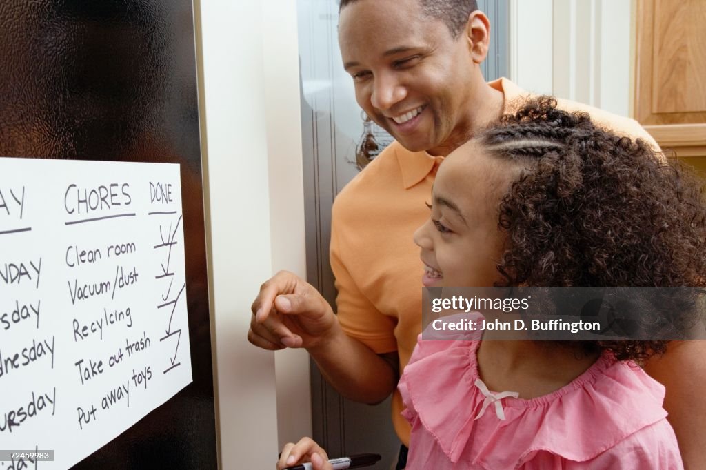 African father and daughter looking at chores chart