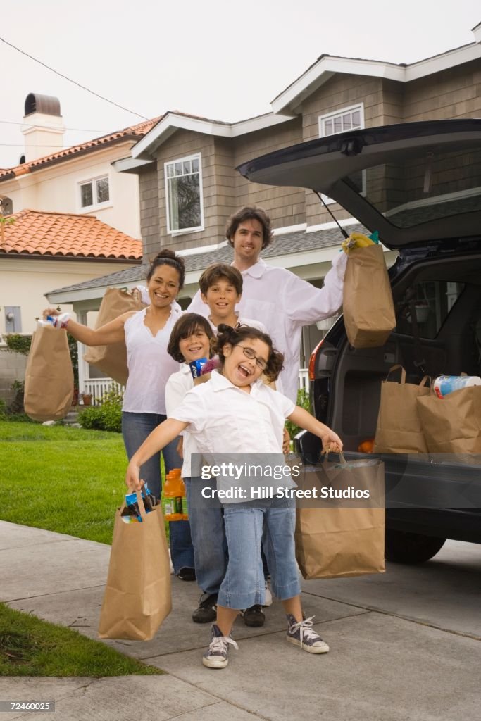 Hispanic family unloading grocery bags from car