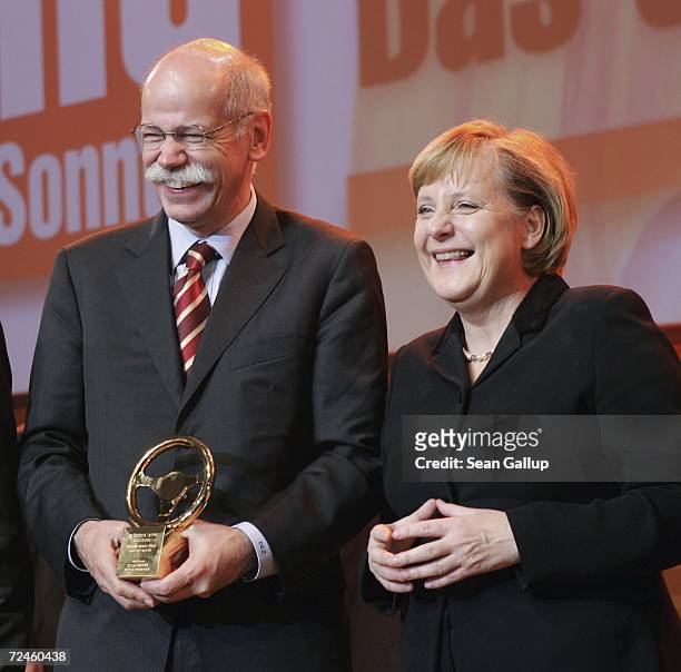 Dieter Zetsche, Chairman of automobile manufacturer DaimlerChrysler, holds his company's award for Best Coupe as German Chancellor Angela Merkel...