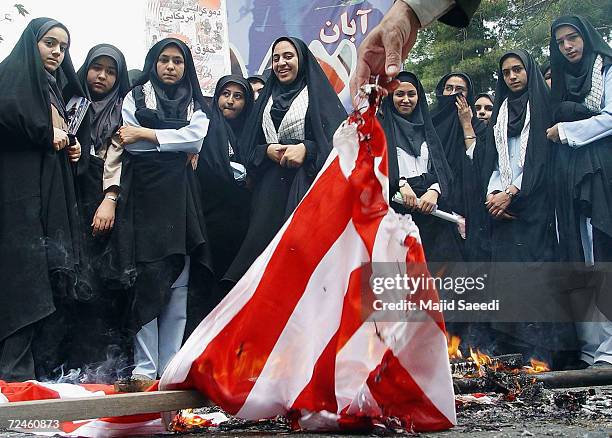 Iranian women watch a U.S. Flag being burned outside the former U.S. Embassy at a gathering to mark the 25th anniversary of the seizure of the U.S....