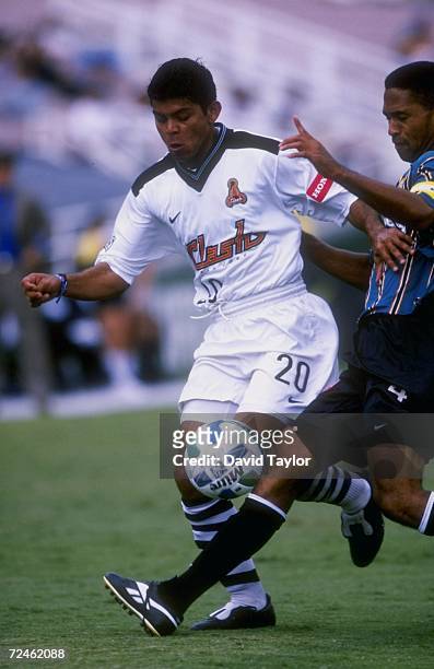 Ronald Cerritos of the San Jose Clash dribbles the ball while being pursued by Robin Fraser of the Los Angeles Galaxy during a game at the Rose Bowl...