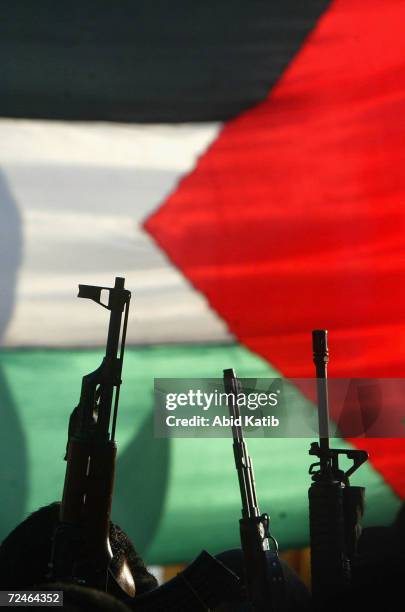 Masked Palestinian gunmen from the Fatah movement hold their weapons in front of the palestinian flag during a march in support for Palestinian...