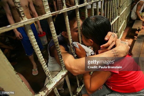 Couple kisses through the bars in a cell packed with several dozen inmates at the Navotas Municipal jail July 17, 2005 in Navotas, Manila,...