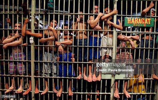Inmates stand on the bars of an overcrowded jail cell at the Navotas Municipal jail July 17, 2005 in Navotas, Manila, Philippines. Economic woes have...