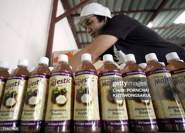 Thai worker packs bottles of mangosteen juice at a factory in Bangkok, 09 November 2006. Thais call mangosteens the "queen of fruit", and growers...