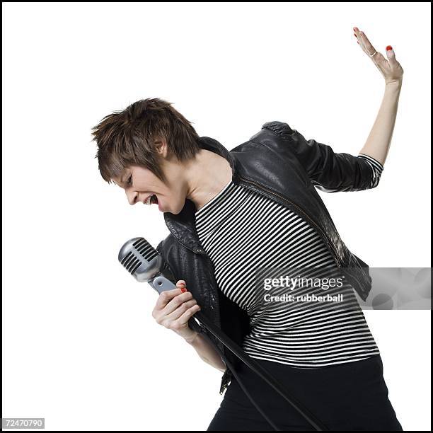 a young woman singing into a microphone - white female singer stock pictures, royalty-free photos & images