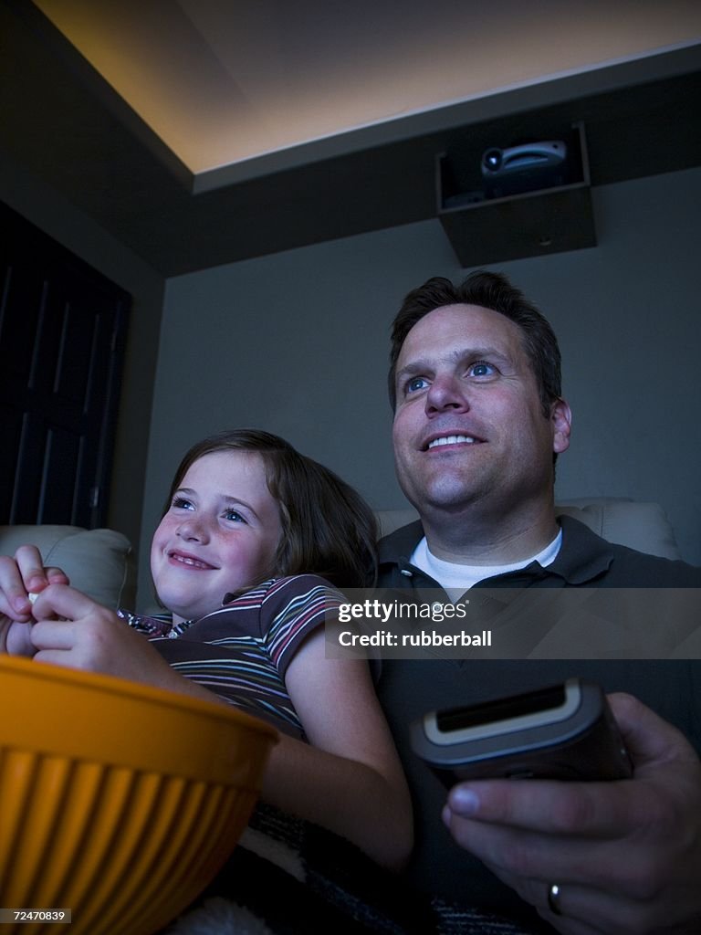 Father and daughters watching movie in home theater