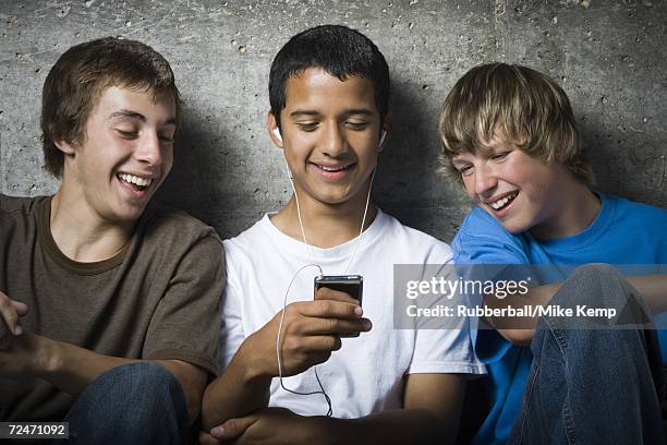 close-up of three teenage boys looking at an mp3 player - beton person close stock-fotos und bilder