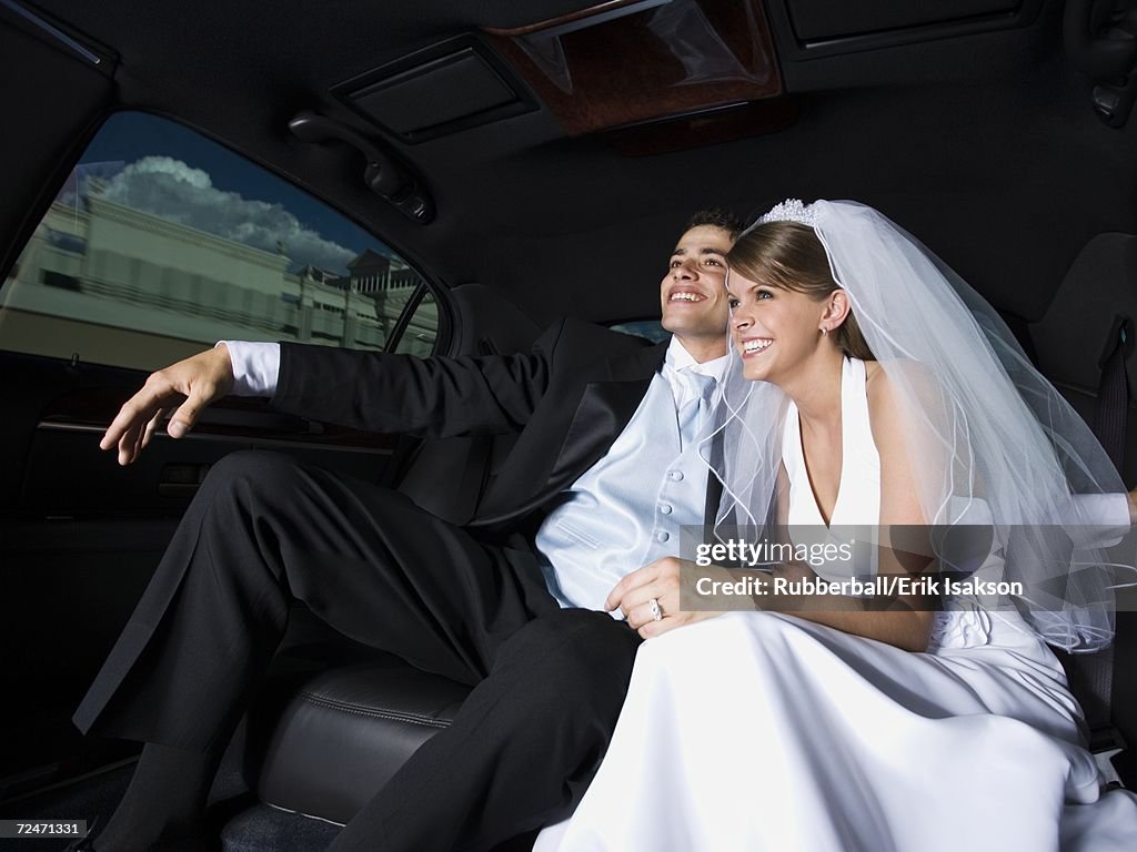 Newlywed couple sitting in a car and smiling