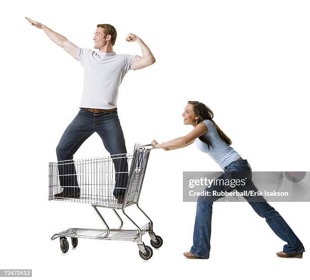 woman pushing shopping cart with boyfriend inside - man pushing cart fun play stock pictures, royalty-free photos & images