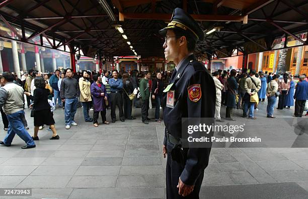 Police officer stands guard at the Hsing Tien Temple where Taiwanese people stand in line to pray as well as vote on March 20, 2004 in Taipei....