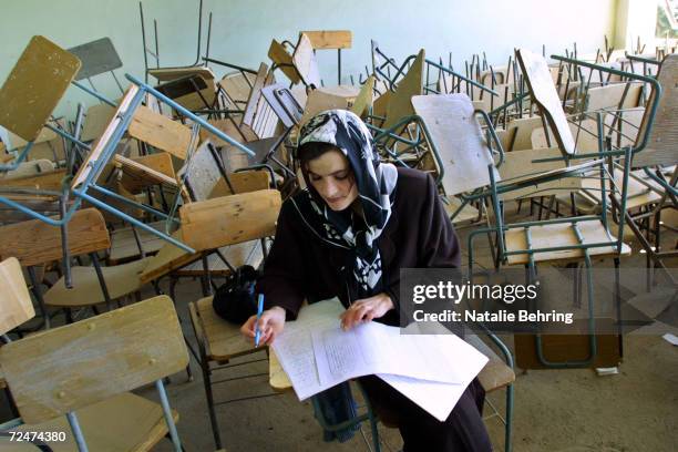 An Afghan woman takes a university entrance exam February 20, 2002 in a classroom destroyed during Afghanistans civil war at Kabuls Polytechnic...