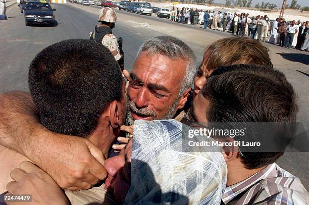 Iraqi prisoners receive a hugs from a relatives after being brought by bus from Abu Ghraib prison to an Iraqi Military base in Baghdad for release on...