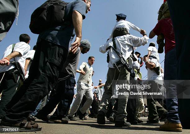 Armed Jewish settlers dance on their way to the Cave of the Patriarchs during Purim festivities March 27, 2005 in the West Bank town of Hebron....