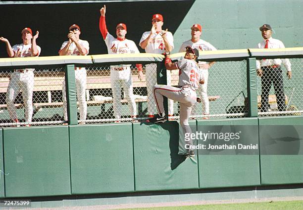 Outfielder Andruw Jones of the Atlanta Braves focuses on the baseball as he climbs the wall in left field to make an attempt at a Ron Gant of the St....