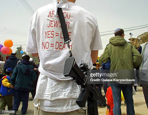 Jewish settler wearing a t-shirt with the inscription: "Are you Jewish?, Yes = Life, No = death" and a mock rifle takes part in Purim festivities...