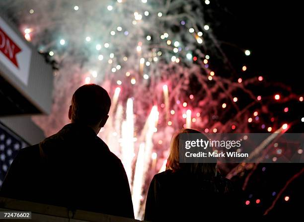 People watch as fireworks explode in the air after U.S. President George W. Bush finished speaking during a campaign rally at the Journal Pavilion...