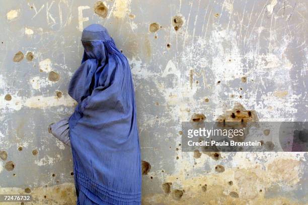 An Afghan widow, who lost her spouse from the fighting in Afghanistan, waits as food is distributed from the Cooperative for Assistance and Relief...