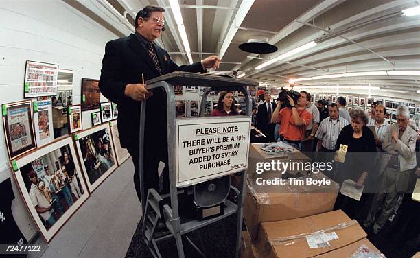 American Auction Associates auctioneer Donald Dodge, center, barks out prices for boxes of Michael Jordan's Restaurant t-shirts, June 6 to be...