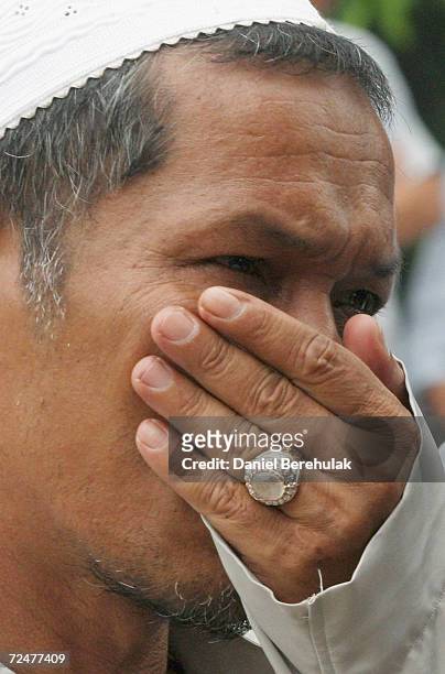 Villagers hold their noses from the smell of the unclaimed bodies of those killed in Wednesday's deadly clash, during a mass funeral ceremony on...