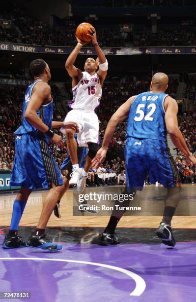 Vince Carter of the Toronto Raptors sends up a jumper from the line as Tracy McGrady and Don Reid of the Orlando Magic look on at Air Canada Centre...