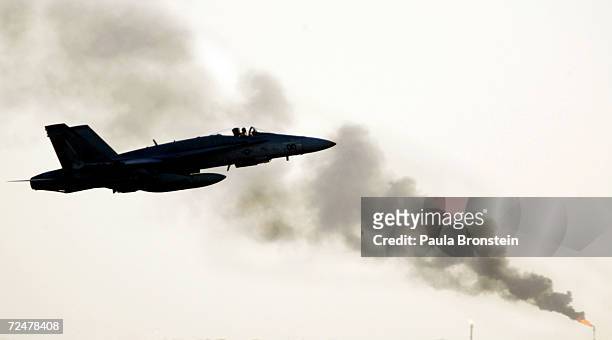 An F/A 18 Marine Corp fighter jet flies through the smoke from a nearby burning oil refinery in the Arabian Gulf near the Iraq border March 14, 2003...