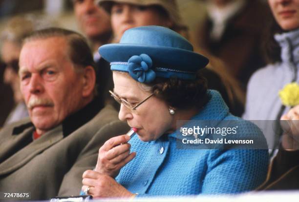 Queen Elizabeth II puts on lipstick in the Royal Box at the Windsor Horse Show on May 11, 1985. Prince Phillip was about to enter the dressage ring...