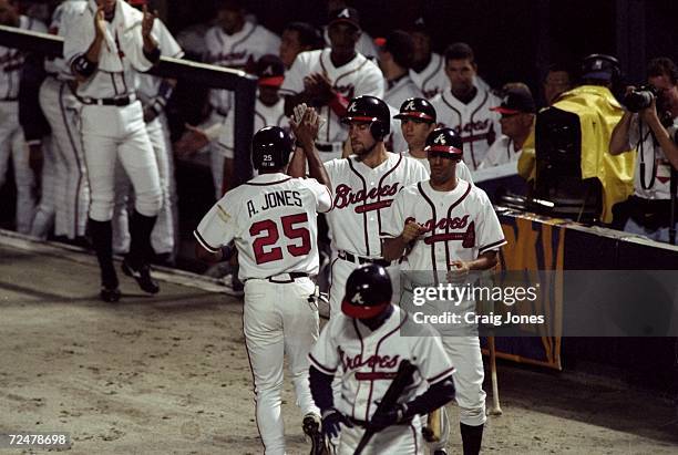 Outfielder Andruw Jones of the Atlanta Braves is greeted by teammates during the National League Championship Series game against the San Diego...