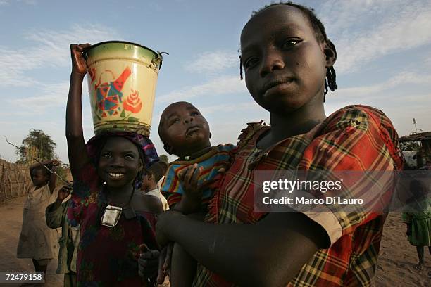 Sudanese refugee girls fetch water and carry the young children on November 8, 2006 in the Goz Amer Refugee Camp, Chad. Since 2004 refugees have fled...