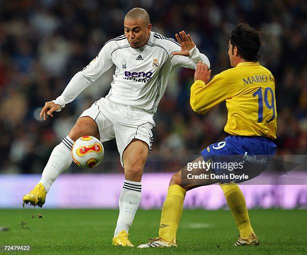 Ronaldo of Real Madrid is challenged by Mario of Ecija in the Kings Cup fourth round second leg match at the Santiago Bernabeu stadium on November 9,...