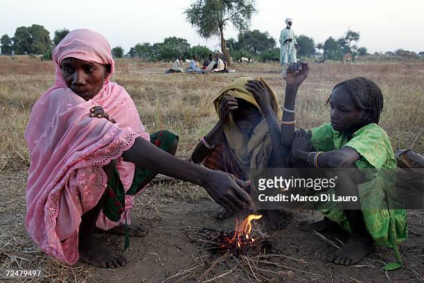 Chadian village women lights a fire watched by her children whilst sheltering under trees after fleeing an attack on their village on November 9,...