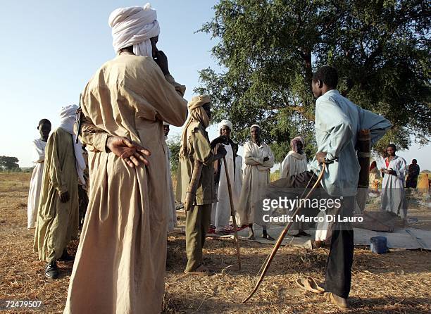 Chadian village elders carry bow and arrows as they discuss how to defend their families after finding shelter under trees after an attack on their...