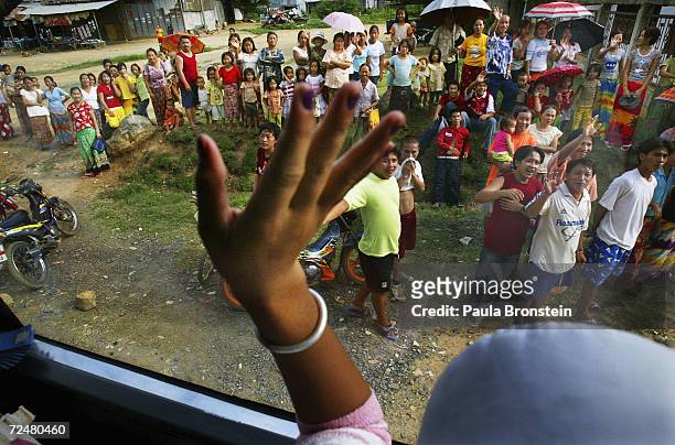 Hmong refugee waves goodbye to friends and relatives leaving the military-run Wat Tham Krabok refugee camp for the last time as she heads to Bangkok...