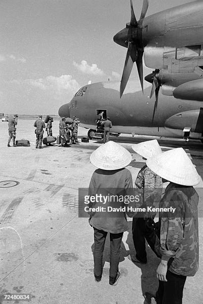 Vietnamese watch U.S. Marines board a C-130 aircraft in 1973 at an airbase in Bien Hoa, Vietnam.