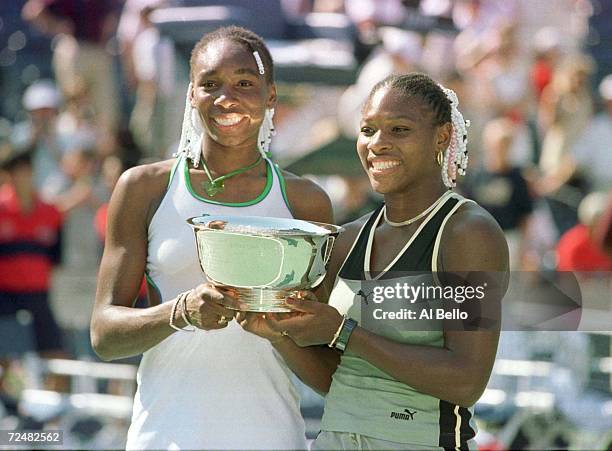 Venus, left, and Serena Williams hold the winners trophy after defeating Sandrine Testud and Chanda Rubin in the doubles final during the US Open at...
