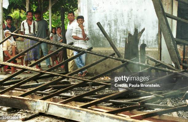 Residents of Lhokseumawe, Indonesia stare at the destroyed Free Aceh Movement headquarters December 8 which was burned down by the Indonesian...