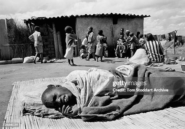 Kenedy Tembo, aged 23, lies sick with AIDS outside the family home where 8 people live in one room in the Mapepe township of Zambia. It is estimated...