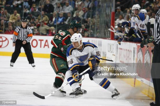 Dan Hinote the St. Louis Blues works for possession of the puck against Nick Schultz of the Minnesota Wild during a preseason game at Xcel Energy...