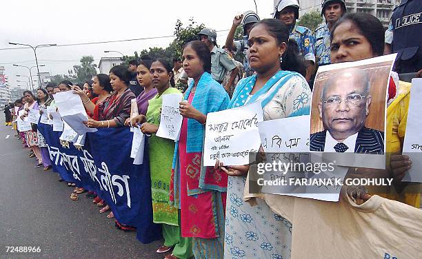 Bangladeshi activists from the youth wing of Awami League hold pictures of chief election commissioner M. A. Aziz during a human chain protest in...