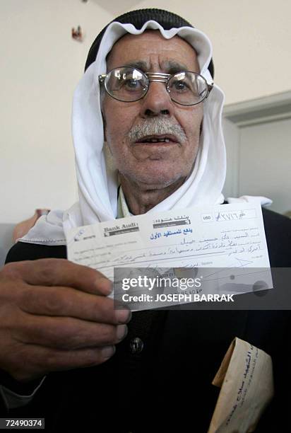 Aita Al-Shaab, LEBANON: Lebanese villager Ali Hussein Jamil shows a check he received from Qatari Mohammed al-Khalifa, the financial manager for...