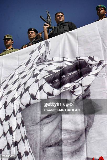 Palestinian security officers stand on the roof of the Muqataa or Palestinian Authority headquarters after a huge banner of the late leader Yasser...