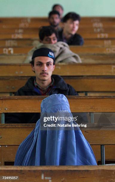 An Afghan woman, wearing a burqa, sits in a lecture hall with male classmates February 20, 2002 as they wait to take a university entrance exam at...