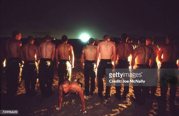 Navy Seal trainee executes pushups in the sand as other trainees stand in line in this undated photo taken in 2000 at the Coronado Naval Amphibious...