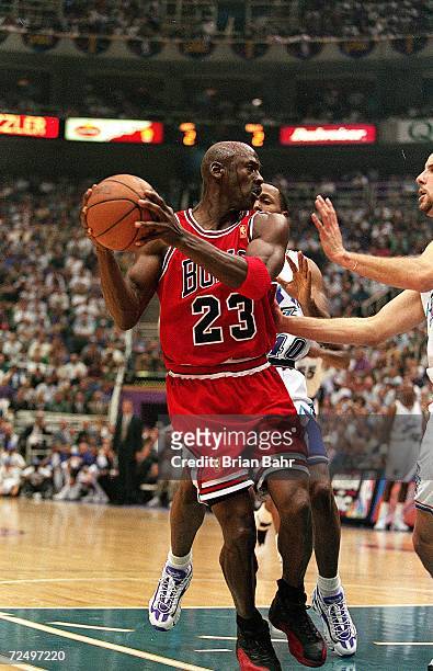 Michael Jordan of the Chicago Bulls grips the ball as he is guarded by Greg Foster of the Utah Jazz during game five of the NBA Finals at the Delta...