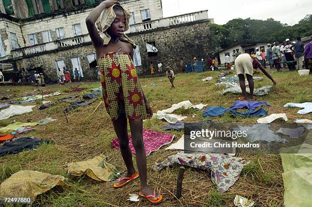 Refugee girl walks admidst laundry scattered around the lawn of a Masonic temple converted into a refugee camp July 15, 2003 in Monrovia, Liberia....