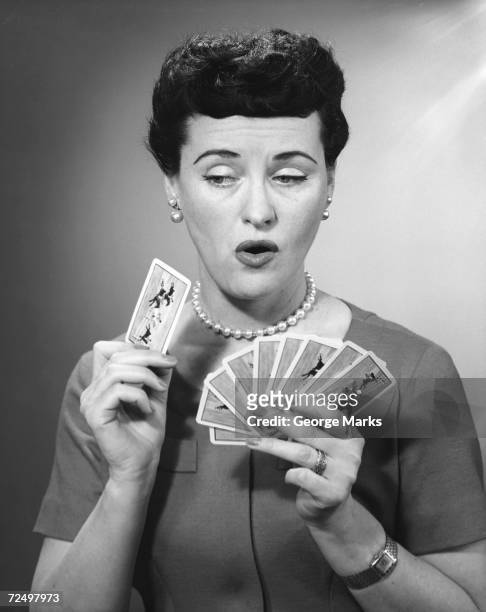 1950s: Woman holding playing cards.