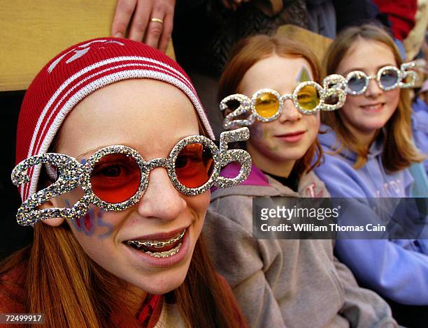 Terri Aristarco, Gina Aristarco, and Rebecca Todd wear "2005" glasses as they watch the Philadelphia Mummers Parade January 1, 2005 in Philadelphia,...