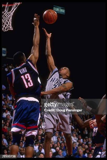 Guard Allen Iverson of the Georgetown Hoyas tries to lift the ball above the long arm of forward Kirk King of the Connecticut Huskies in this Big...