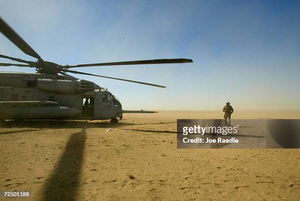 Marine Paul T. Williams from Beaverton, Michigan walks past the Super Stallion helicopter before take off March 14, 2002 after refueling Marine Cobra...